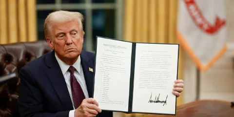 Photo · President Trump holds a signed executive order, 2025
